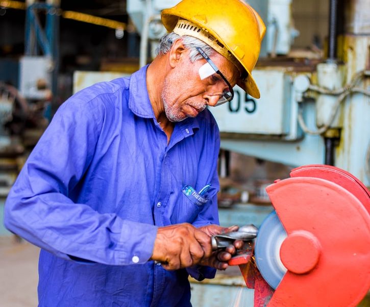 man grinding metal tool in industrial machinery